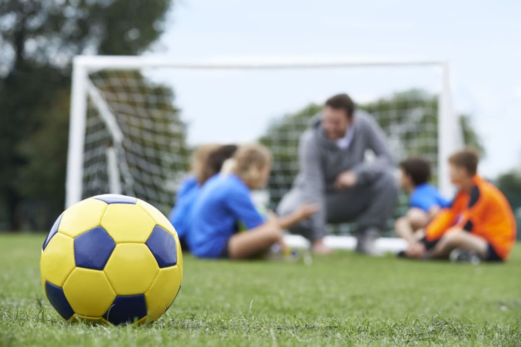 Children with a teacher and a soccer ball in the foreground