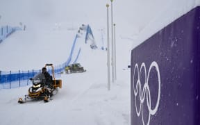 A snowmobile drives past a placard displaying olympic rings, shortly after the cancellation due to weather conditions of the snowboard women's slopestyle final run 1 during the Milano Cortina 2026 Winter Olympic Games at Livigno Snow Park, in Livigno (Valtellina), on February 17, 2026.