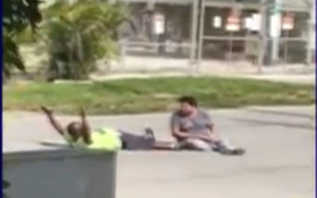 A screenshot of the video showing Charles Kinsey (L) lying on the ground with his hands up.