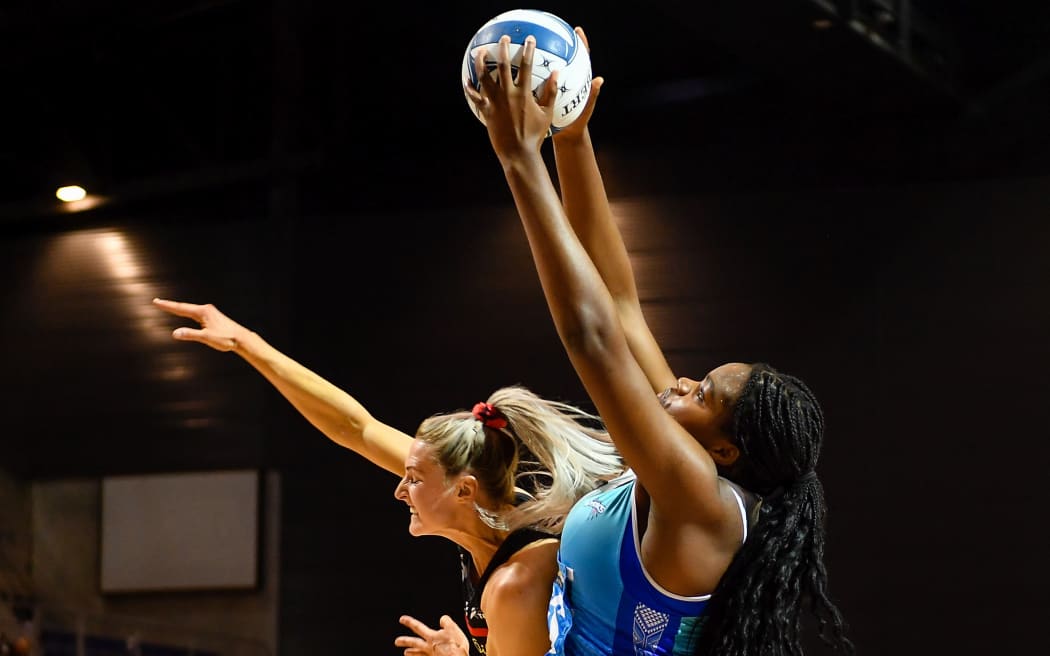 Mystics shooter Grace Nweke stretches high over Tactix defender Jane Watson