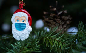 This picture taken in Paris on December 22, 2020 shows a Christmas Santa Claus decoration, with a protective mask. (Photo by JOEL SAGET / AFP)