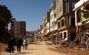 Volunteers pass damaged homes in Derna. Rescuers have been sifting through mud and rubble searching for people missing after the flash flood.