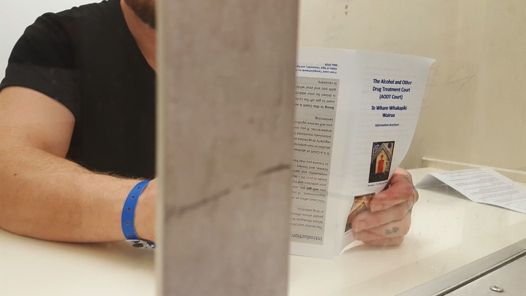 A drug court applicant in the holding cells looks over a leaflet about the court before his appearance