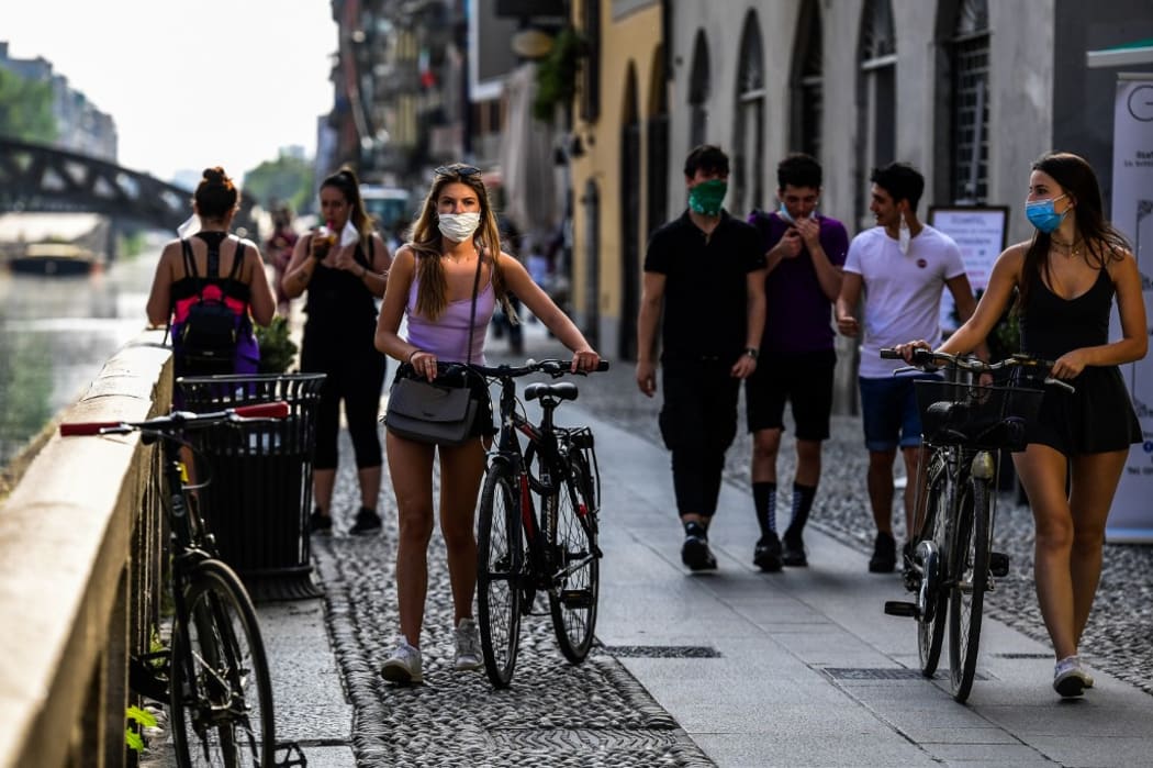 People stroll along the Navigli canals in Milan on May 8, 2020 during the country's lockdown aimed at curbing the spread of the COVID-19 infection, caused by the novel coronavirus.