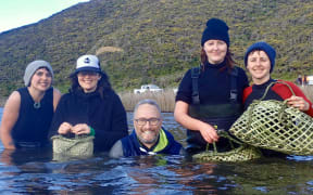 Amber McEwan (second from left) and Holden Hohaia (centre) were part of the small team that braved the wintry waters of Lake Kohangapiripiri to collect 150 kakahi.