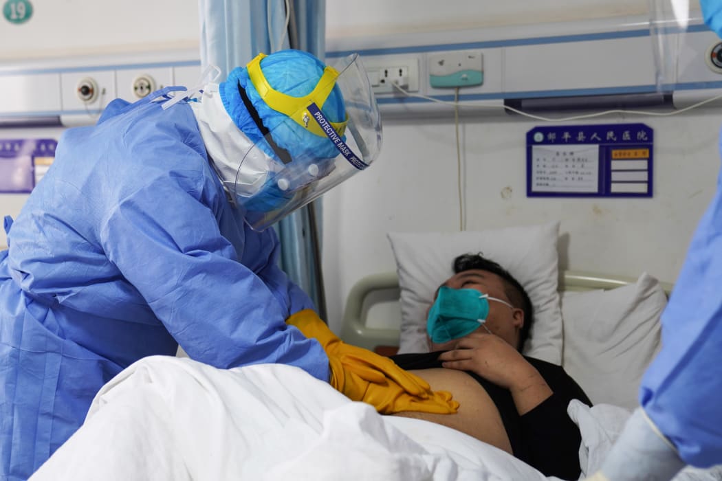 A medical staff member checking a patient infected by the novel coronavirus in an isolation ward at a hospital in Zouping in China's eastern Shandong province.