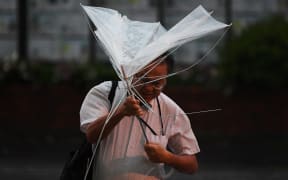 A man with an umbrella crosses a street early morning under the rain as a typhoon hits Tokyo on September 9, 2019.