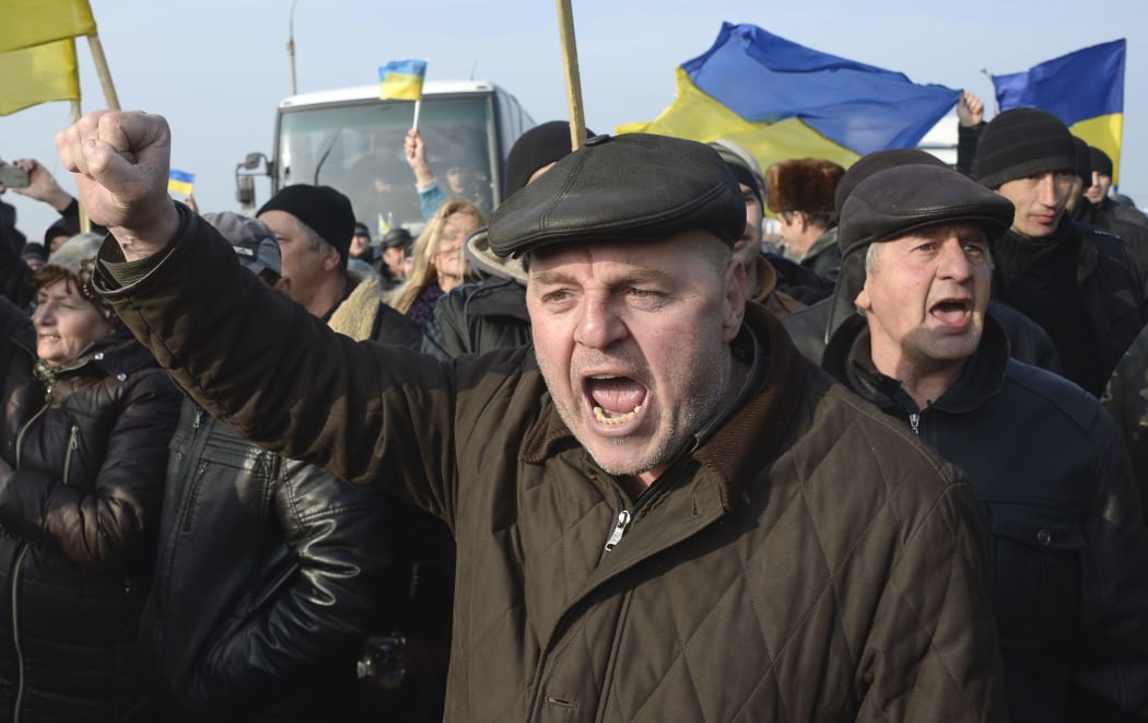 Ukrainians carrying their country's flags stage a protest at the Chongar check point blocking the entrance to Crimea.