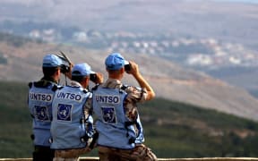 Members of the United Nations Truce Supervision Organization (UNTSO) use binoculars to look at the Israeli side from the southern Lebanese village of Kfar Kila, 14 October 2006.