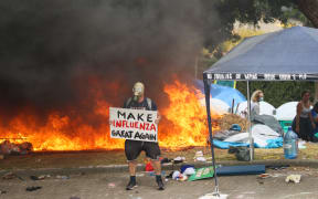 A protest stands in front a fire with a puzzling sign.