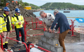 chief military putting the first stone of the docking quay.