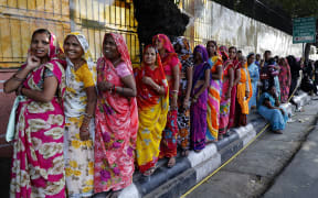 Indian women stand in a queue to deposit and exchange discontinued rupees outside a bank in Jaipur, India.