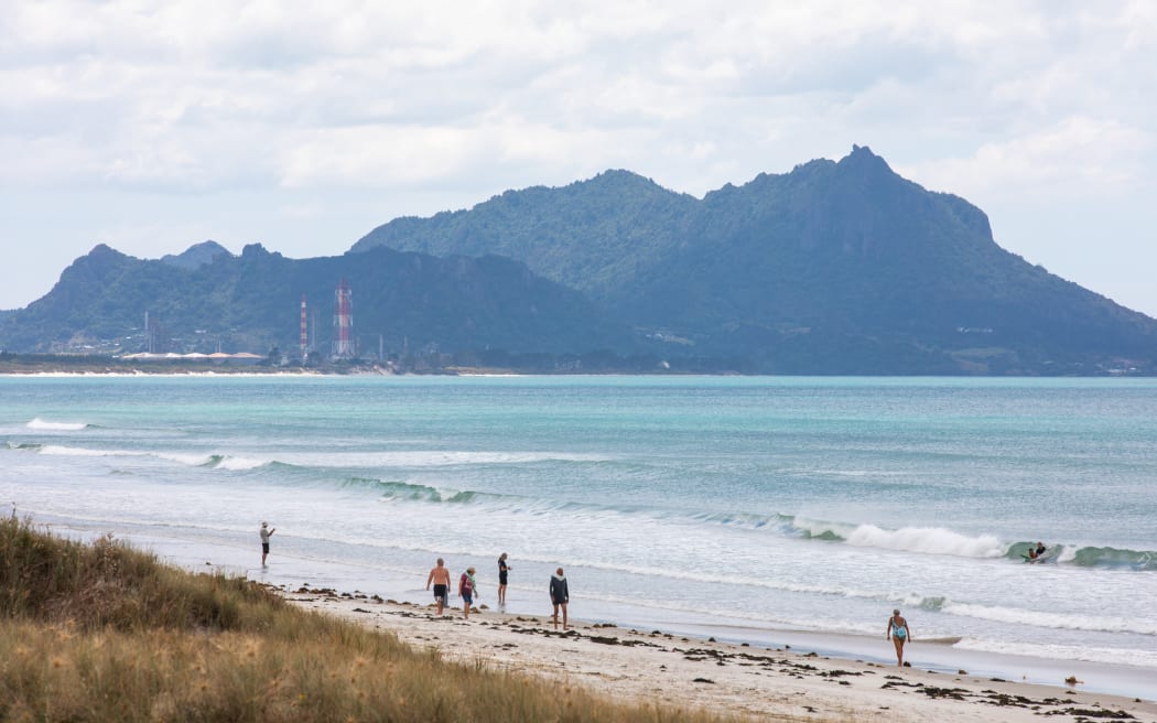 Marsden Point with people enjoying Ruakākā beach in the foreground