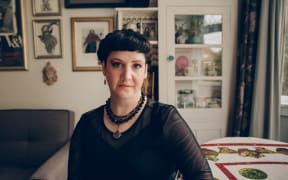 Una Cruickshank - a woman with short black hair and a black top - looks enquiringly at the camera.