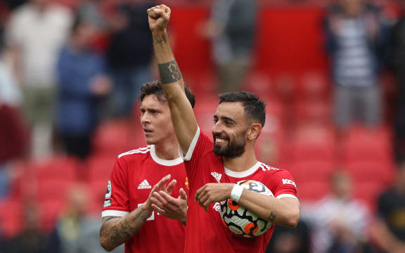 Manchester United's Portuguese midfielder Bruno Fernandes holds the match ball as he reacts at the final whistle during the English Premier League football match against Leeds United at Old Trafford in Manchester, north west England, on August 14, 2021.
