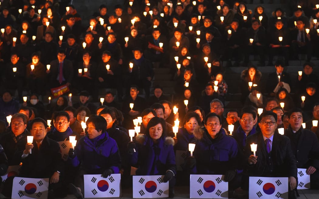 Lawmakers and members of South Korea's main opposition Democratic Party hold candles at a protest urging the impeachment of then-President Park Geun-Hye at the National Assembly in Seoul on 8 December, 2016.