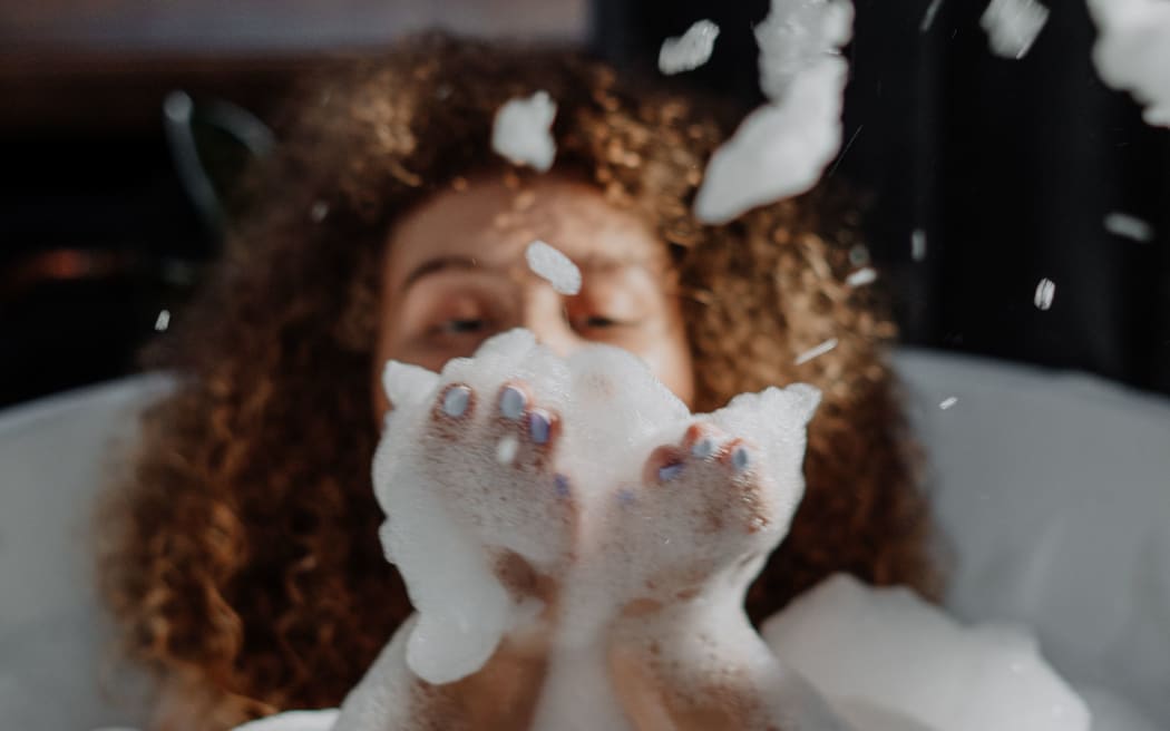 woman blowing bubbles in bath
