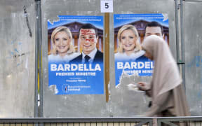 A woman walks past election campaign posters in Paris.