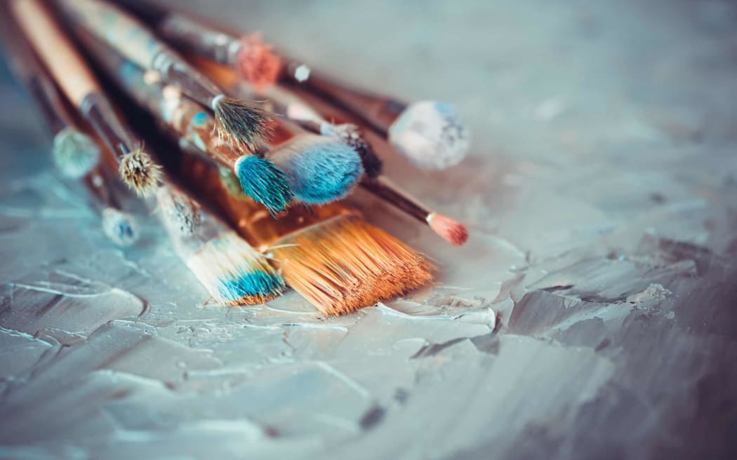 Paintbrushes on artist canvas covered  with oil paints