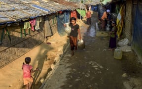 A Rohingya refugee girl walks back to her makeshift house after collecting drinking water in Jamtoli refugee camp in Ukhia on 11 December 2019.