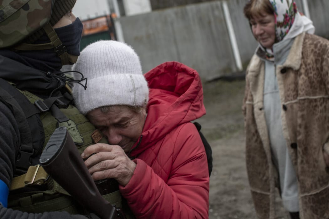 An elder woman weeps as she welcomes Territorial Defense Forces' members on 1 April, 2022 after they recovered the Nova Basan village on the eastern of Kyiv, Ukraine, from the Russian army.