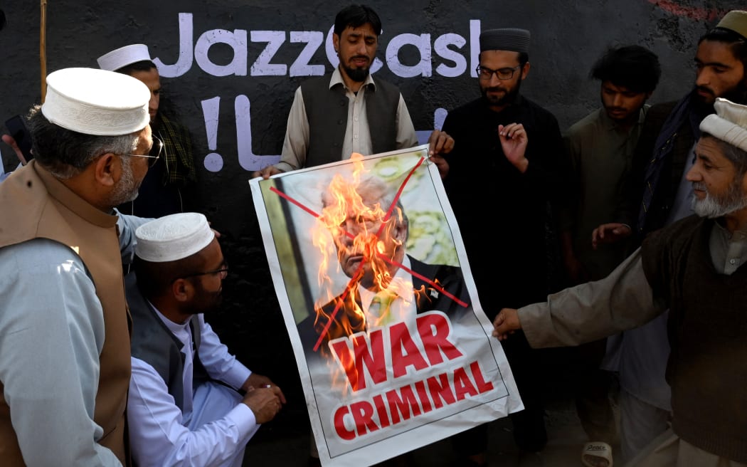 Activists and supporters of the Jamaat-e-Islami party burn a poster of US President Donald Trump during an anti-US and Israel protest in Peshawar on March 2, 2026 after the death of Iran's supreme leader Ayatollah Ali Khamenei amid US-Israel strikes. The death toll from Pakistan's violent weekend protests over the killing of Iran's supreme leader has reached at least 25, according to an AFP tally on March 2. (Photo by Abdul MAJEED / AFP)