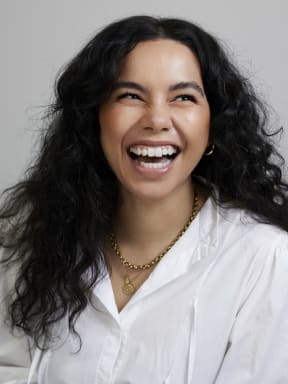 Courtney Dawson laughs. She is wearing a white shirt and a gold chain necklace.