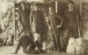 WW1 soldiers posing in front of piles of sheep fleeces at Oatlands Park, Surrey, England.