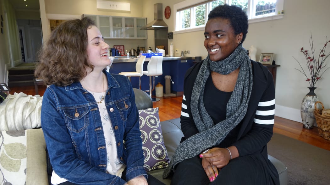 2 students sit on a couch at home