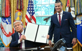 US President Donald Trump shows a signed executive order as the Secretary of Defense Pete Hegseth looks on in the Oval Office of the White House in Washington, DC on September 5, 2025. Trump on Friday signed an order rebranding the Department of Defense as the Department of War, saying it sent a "message of victory" to the world. (Photo by Mandel NGAN / AFP)