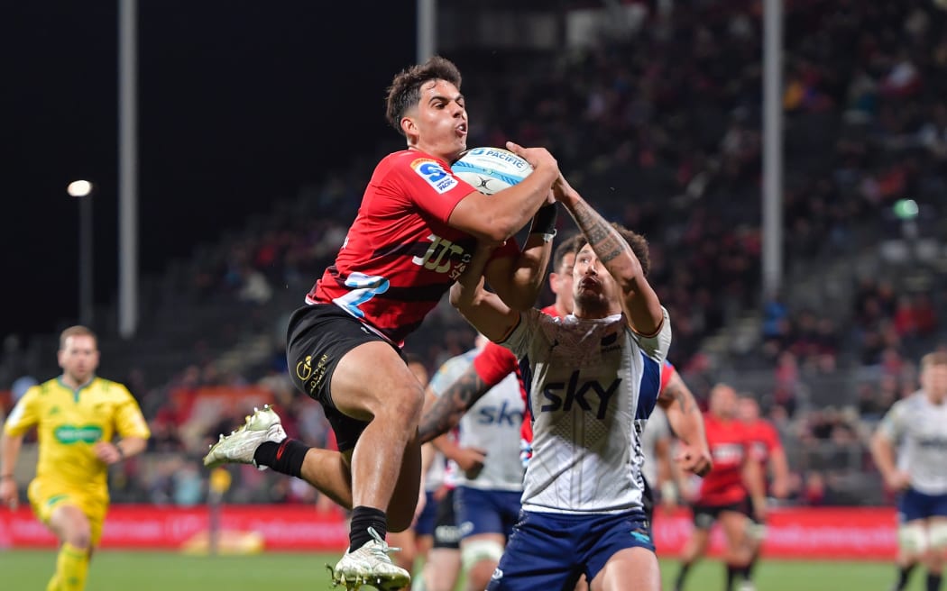 Noah Hotham of the Crusaders grabs the ball from William Havili of Moana Pasifika to score.