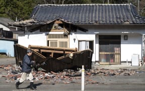 Sushi maker Akio Hanzawa walks in front of his damaged restaurant in Shiroishi, Miyagi prefecture on 17 March  2022, after a 7.3-magnitude earthquake jolted east Japan the night before.