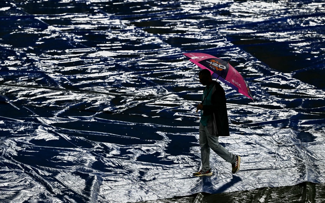 A ground staff walks over the covered field after the 2026 ICC Men's T20 Cricket World Cup Super Eight match between Pakistan and New Zealand was called off due to rain at the R Premadasa Stadium in Colombo on February 21, 2026. (Photo by Ishara S. KODIKARA / AFP)