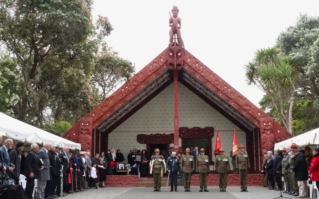 Army leaders, with Tā (Sir) Robert “Bom” Gillies, salute in front of Te Whare Rūnanga [the carved meeting house].