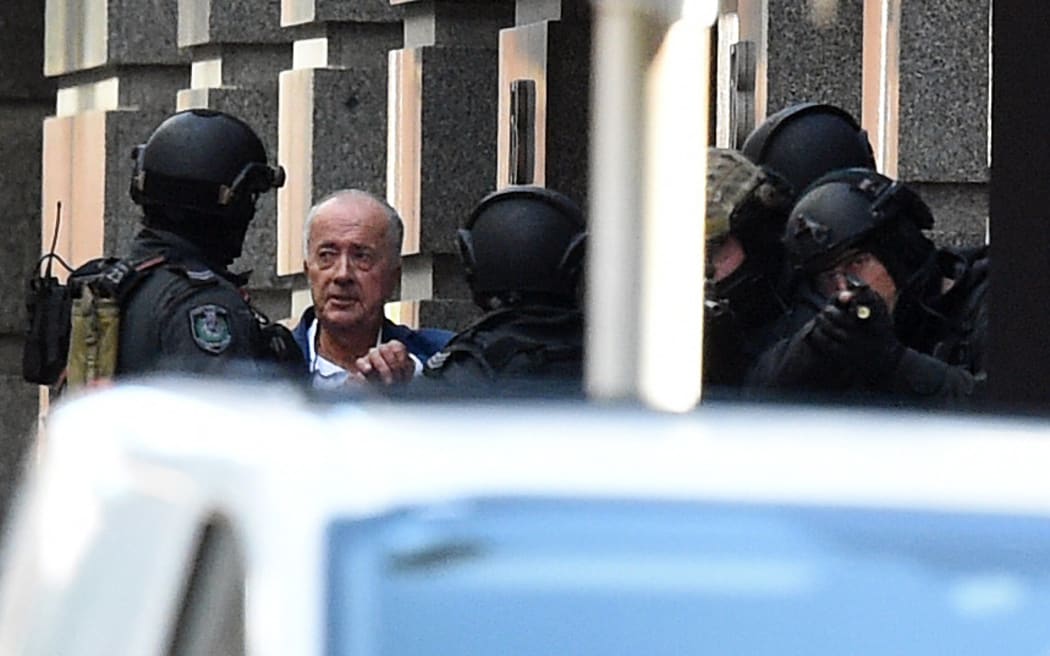 A released hostage (second from left), speaks with NSW Public Order and Riot Squad Police.
