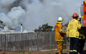 Firefighters secure a house as smoke from bushfires rises in Penrose, in Australia's New South Wales state on January 10, 2020.