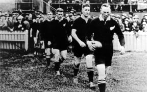 Jock Richardson leads the All Black Invincibles team out onto the field prior to their test match against Ireland, Dublin, 1 November, 1924.