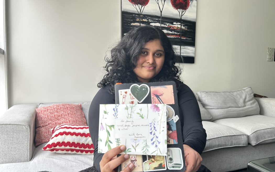 Picture of a woman showing a letter envelope, the envelope has floral patterns printed on it.