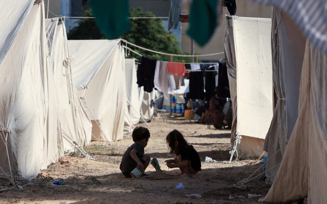 Children play among tents set up for Palestinians seeking refuge on the grounds of a United Nations Relief and Works Agency for Palestine Refugees (UNRWA) centre in Khan Yunis in the southern Gaza Strip on October 19, 2023, amid the ongoing battles between Israel and the Palestinian group Hamas. (Photo by MAHMUD HAMS / AFP)