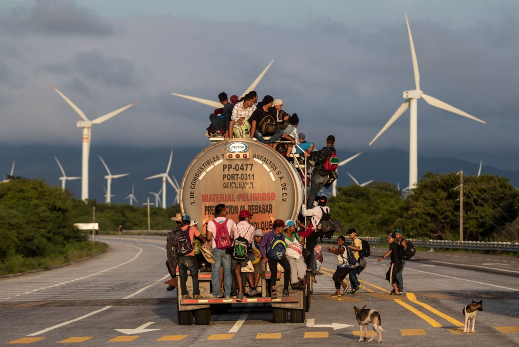 A truck carrying mostly Honduran migrants taking part in a caravan heading to the US, passes by a wind farm on their way from Santiago Niltepec to Juchitan, near the town of La Blanca in Oaxaca State, Mexico.