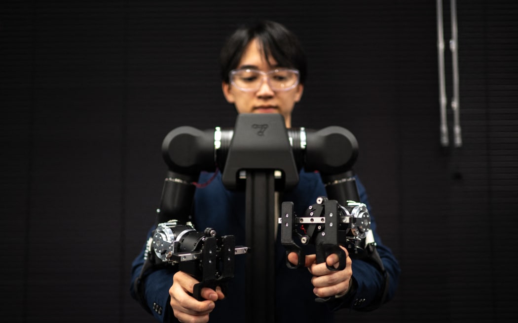 Hiro Yamamoto, CEO of company Enactic,  tele-operating an OpenArm humanoid robotic arm at his office.