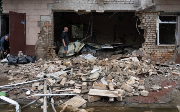 A local resident clears debris of a shop destroyed after a Russian shelling in Kherson, on June 12, 2023, as the region deals with massive flooding from the destruction of Kakhovka hydroelectric power plant dam. (Photo by Oleksii FILIPPOV / AFP)