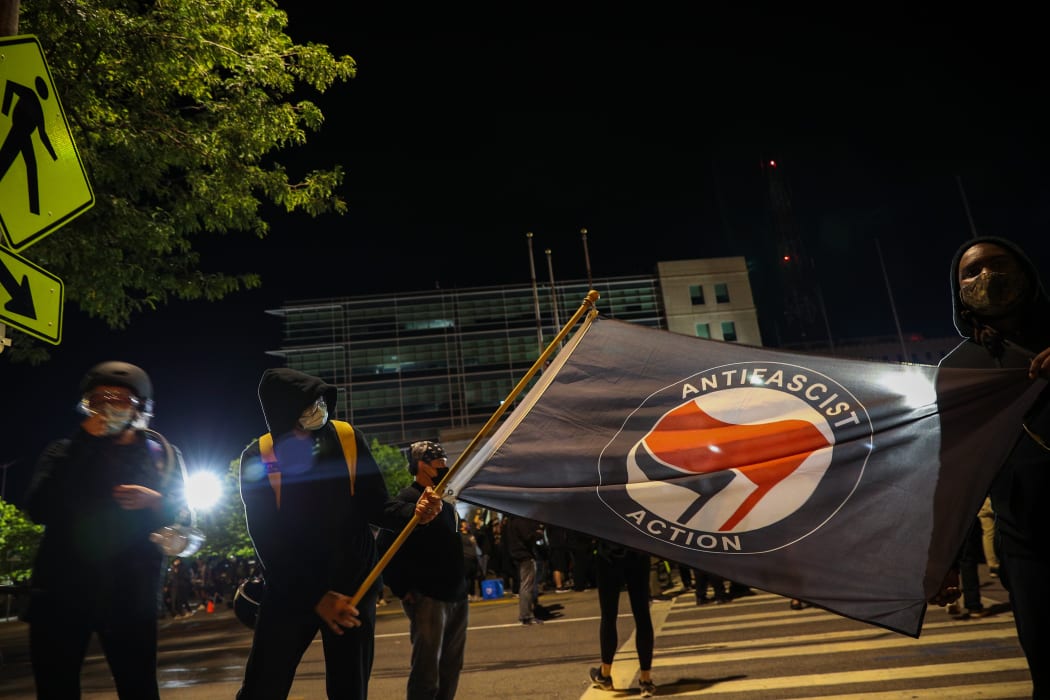 A man holds an anti-fascism flag as hundreds of demonstrators gather and march to the City Public Safety Building over Daniel Prude's death in Rochester, New York, United States on September 6, 2020.