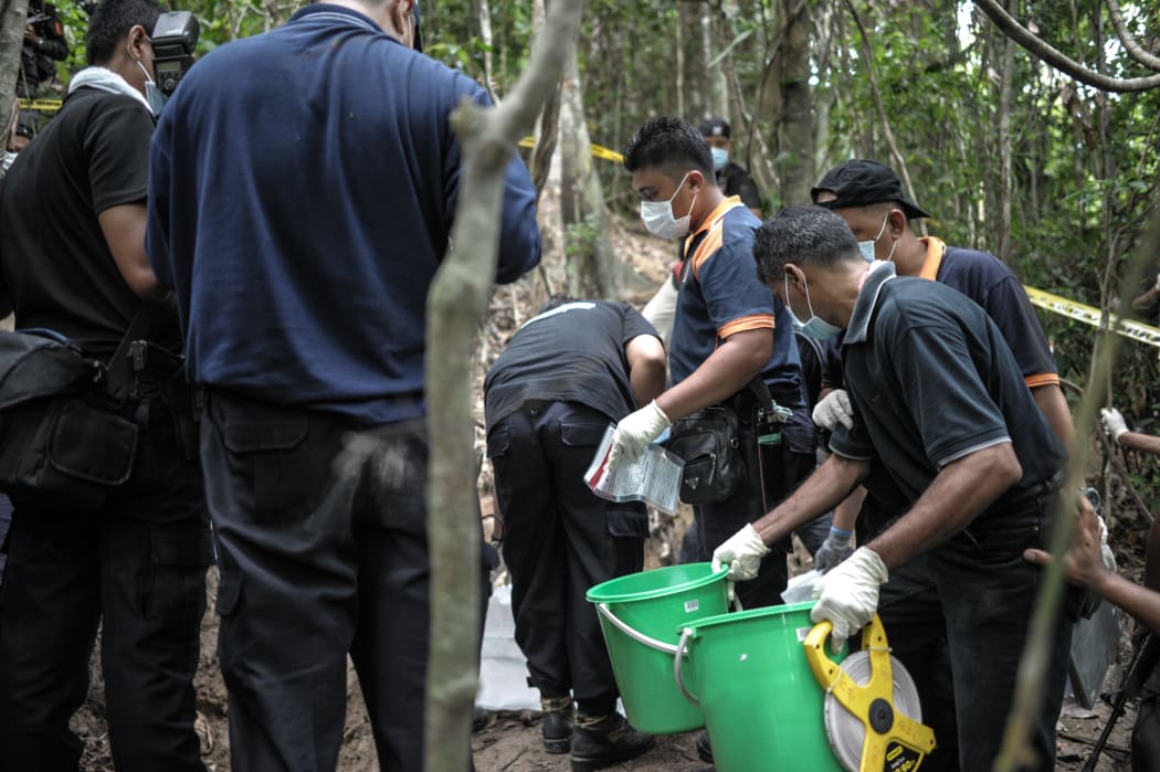 A Royal Malaysian Police forensics team handles exhumed human remains at a grave site near an abandoned migrant camp used by people-smugglers.
