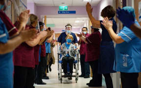 Margaret Keenan (C), 90, is applauded by staff as she returns to her ward after becoming the first person to receive the Pfizer-BioNtech Covid-19 vaccine at University Hospital in Coventry, central England, on December 8, 2020.
