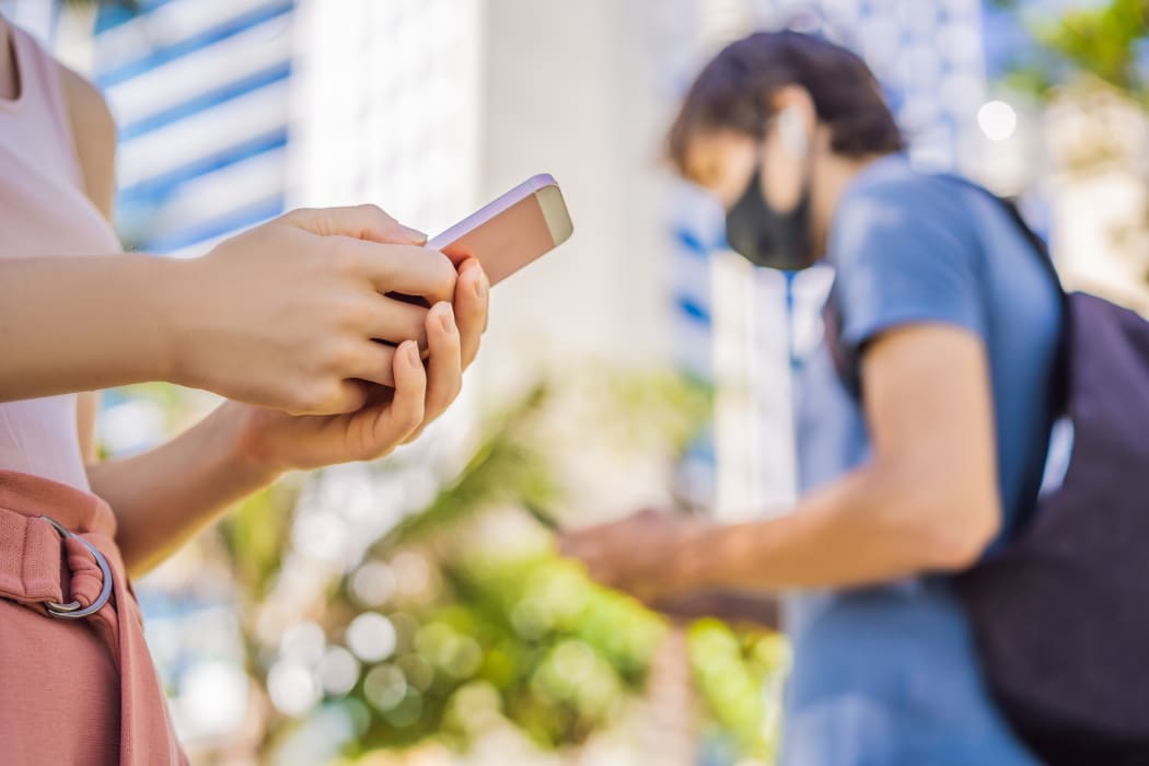 Contact tracing app COVID-19 pandemic coronavirus. People wearing masks using phones.