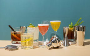 Composition with alcoholic cocktails on podiums and bar tools on colored background