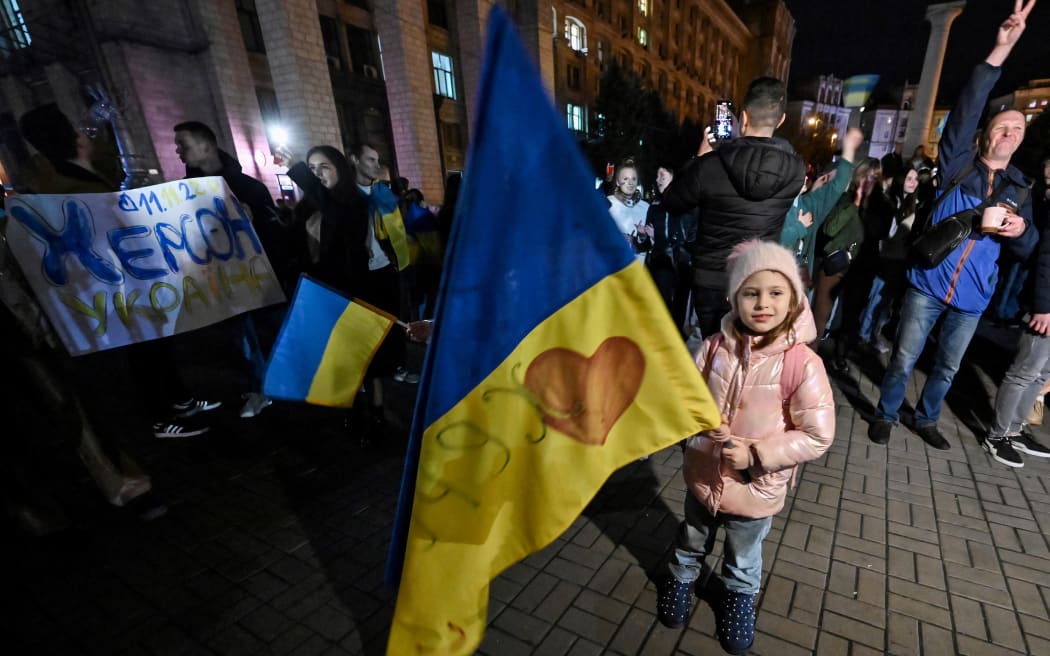 A child holds a Ukranian flag as people gather in Maidan square to celebrate the liberation of Kherson, in Kyiv on November 11, 2022.