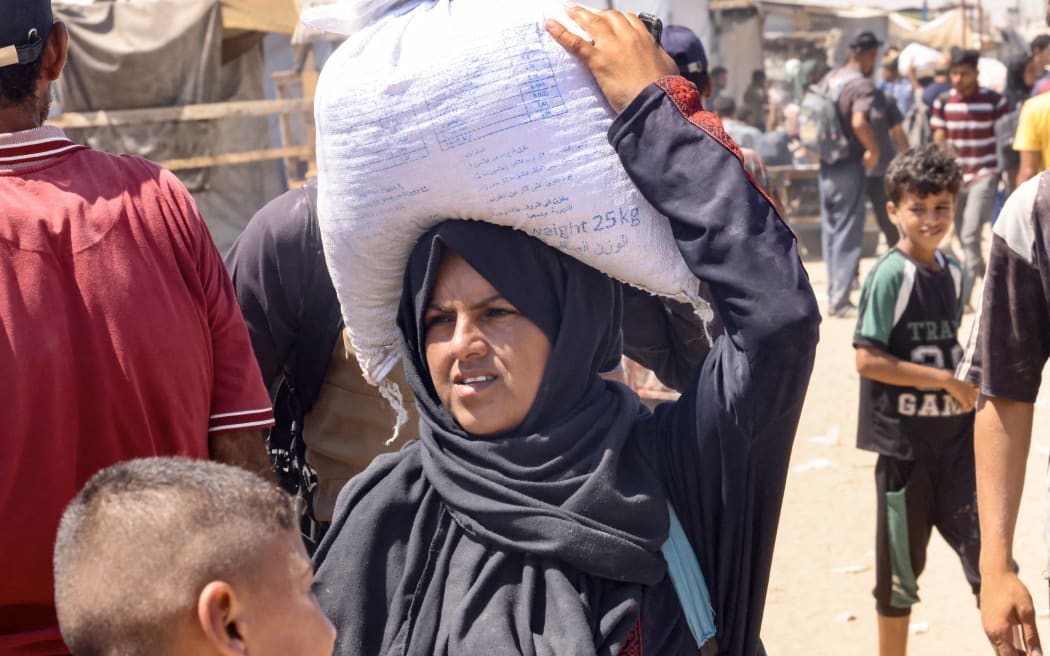 A Palestinian woman carries a bag of food on her head in the al-Mawasi camp in Rafah in the southern Gaza Strip.