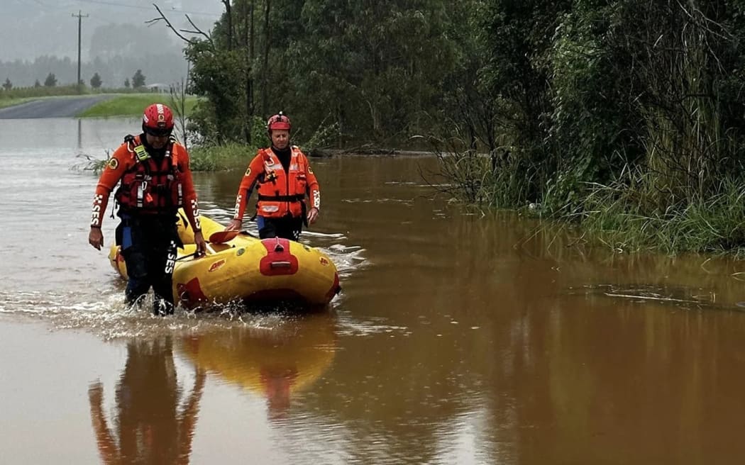 Lismore State Emergency Service officers wade through a river.